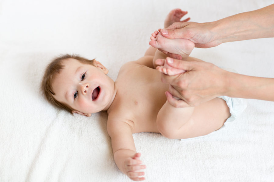 Mão mexendo as pernas do bebê para poder aliviar as colicas