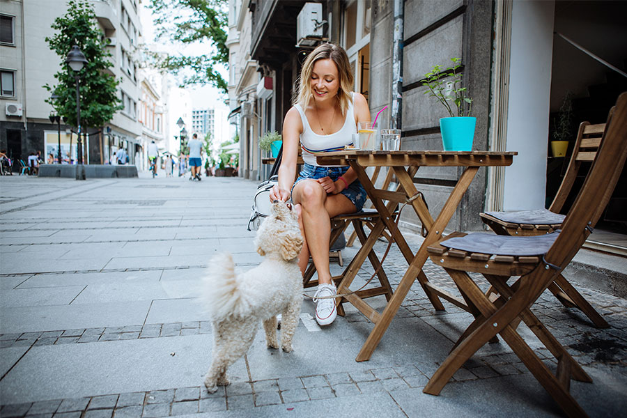 Moça sentada em um café na rua com seu cachorro