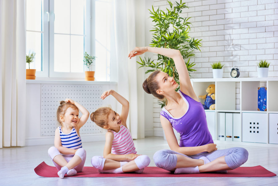 Crianças pequenas praticando exercício físico na infância junto de sua mãe