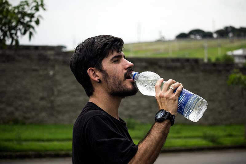 Homem ao ar livre bebendo água de uma garrafa