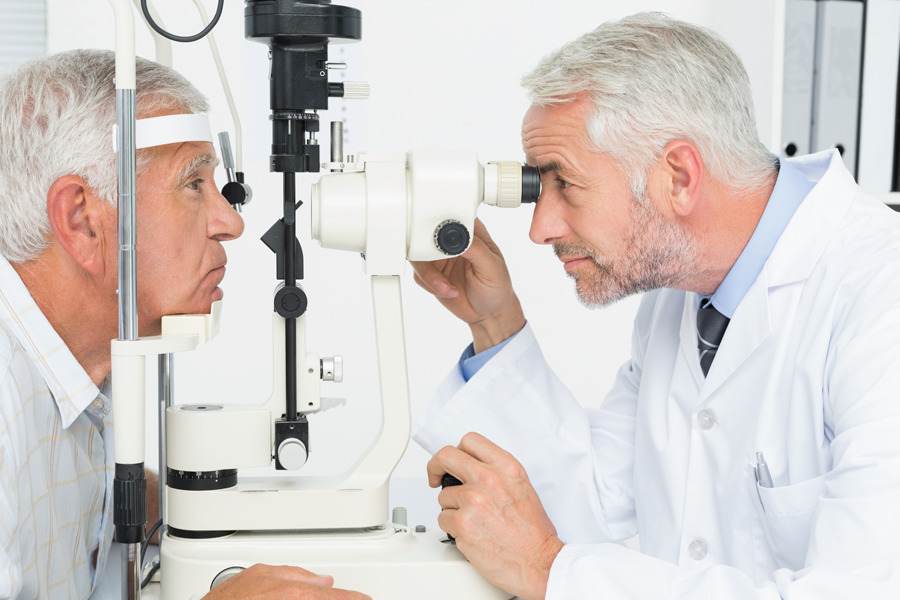 Oftalmologista homem examinando o olho de um senhor para ver se ele precisa de cirurgia de catarata