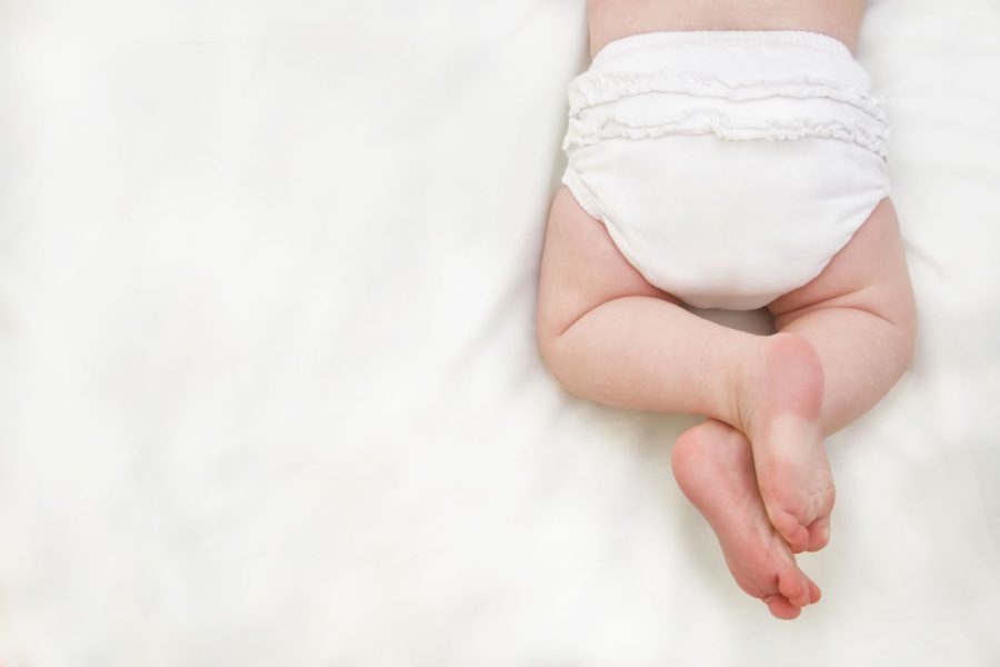 Pernas de um bebe usando fraldas isoladas em um fundo branco representando o desfralde