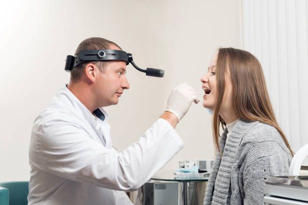 Otorrinolaringologista examinando a garganta de uma jovem