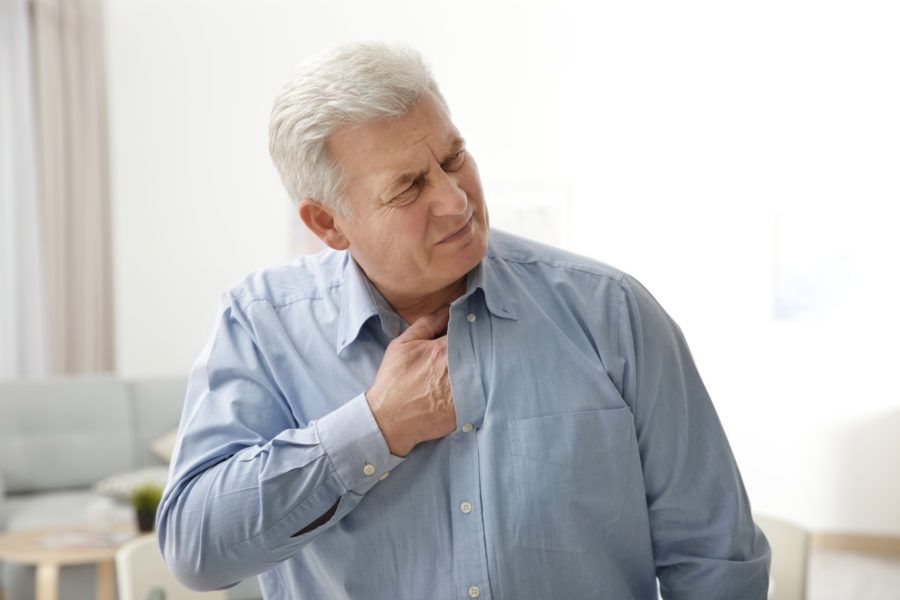 Homem idoso com aterosclerose com a mão no peito sinalizando dores nessa região