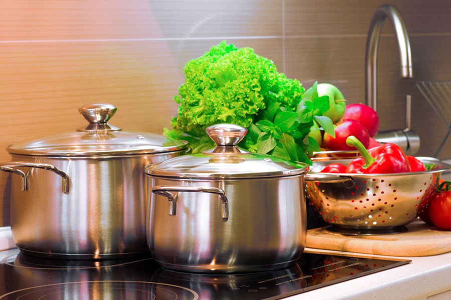 Panelas, vasilhas de metal e alimentos em cima de uma bancada de cozinha