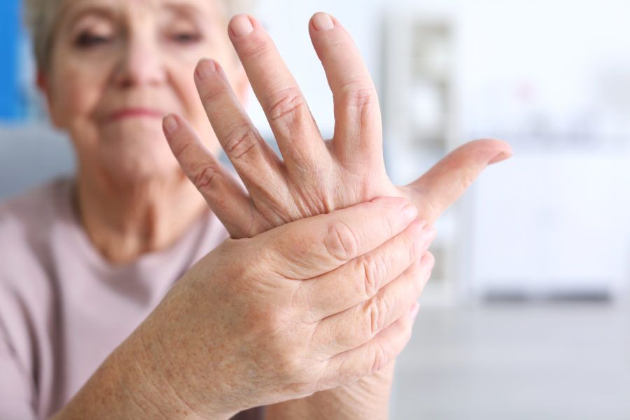 Mulher idosa segurando sua mão que está doendo por causa de lesões nos ossos, a síndrome do túnel do carpo