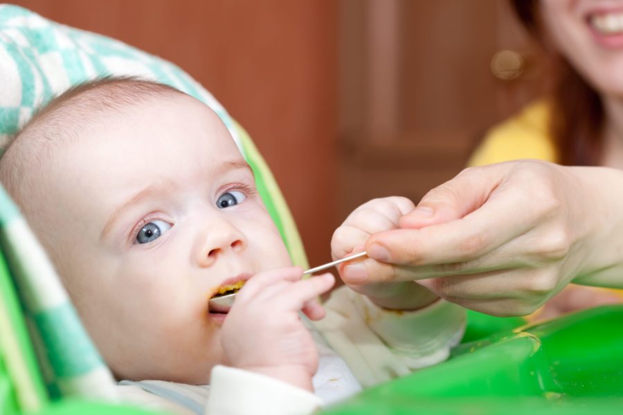 Mãe alimentando seu bebê com papinha para promover a saúde intestinal na infância