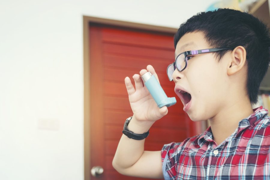 Garoto usando uma bombinha para asma em casa