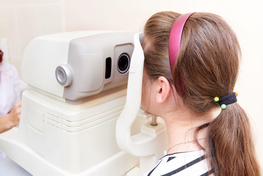 Menina fazendo uma exame de vista em um aparelho