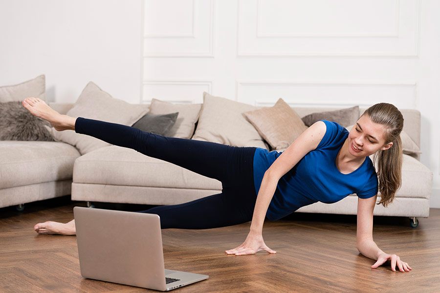 Durante a quarentena, mulher praticando exercício físico na sala de casa com a ajuda de um professor à distancia