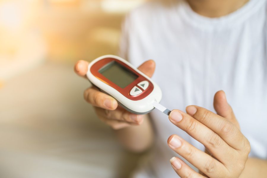 Mão de uma mulher usando o medidos de glicose para saber a taxa de açúcar no sangue e ver como anda a diabetes