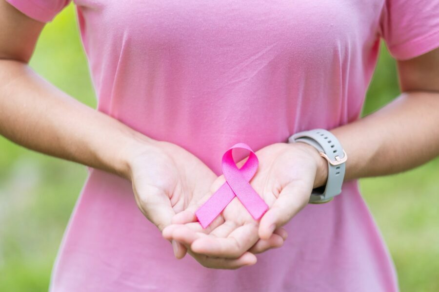 Mulher segurando um fita rosa para alertar sobre o câncer de mama e o outubro rosa