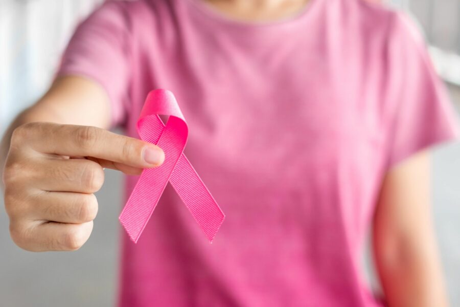 Mulher segurando uma fita rosa para alertar sobre o câncer de mama e o outubro rosa