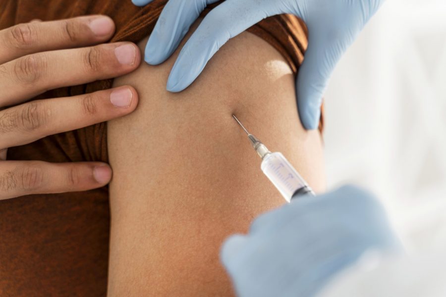 Close do braço de um adulto recebendo uma vacina relaciona ao trabalho por um médico